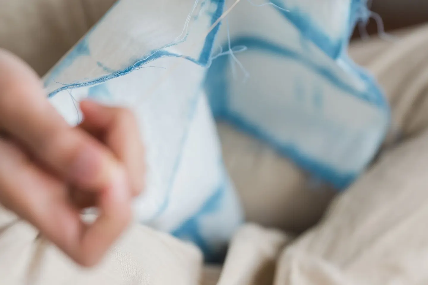 Gros plan sur une personne cousant un tissu à la main