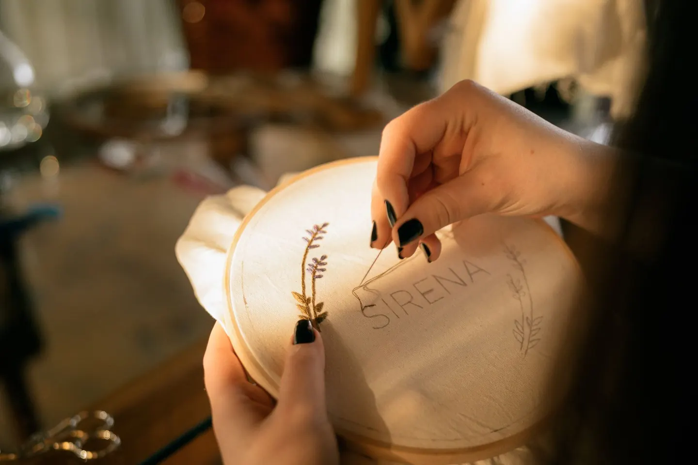 Mains brodant un motif sur un tissu tendu dans un tambour