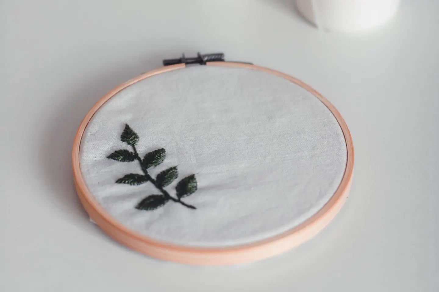 Broderie de feuilles sur tissu, accompagnée de bougies