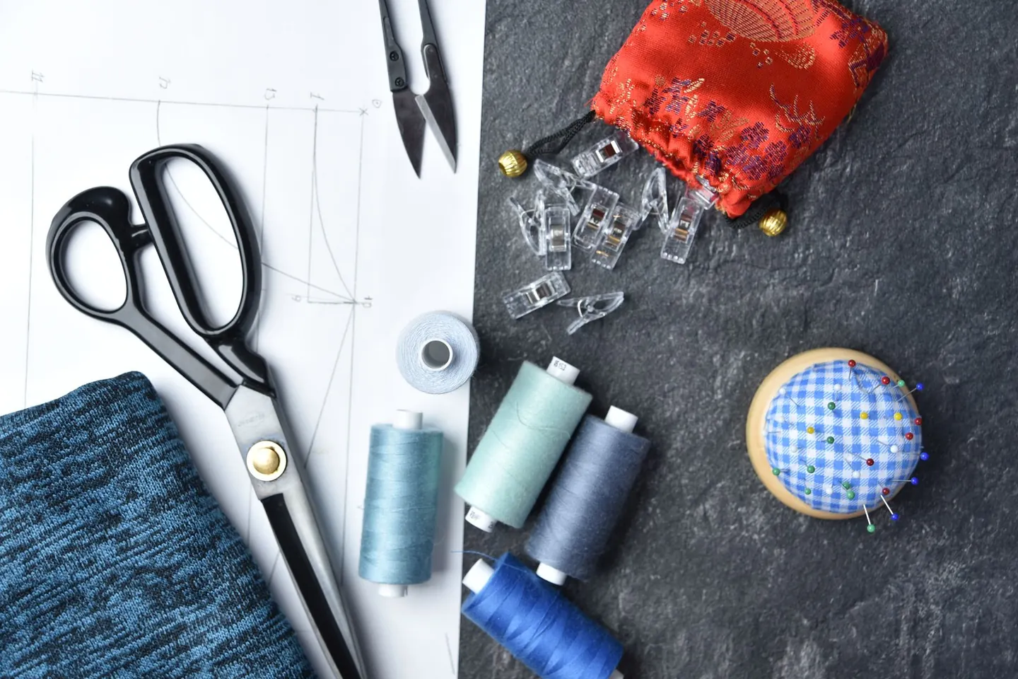 Fils, ciseaux et morceaux de tissu disposés sur un établi