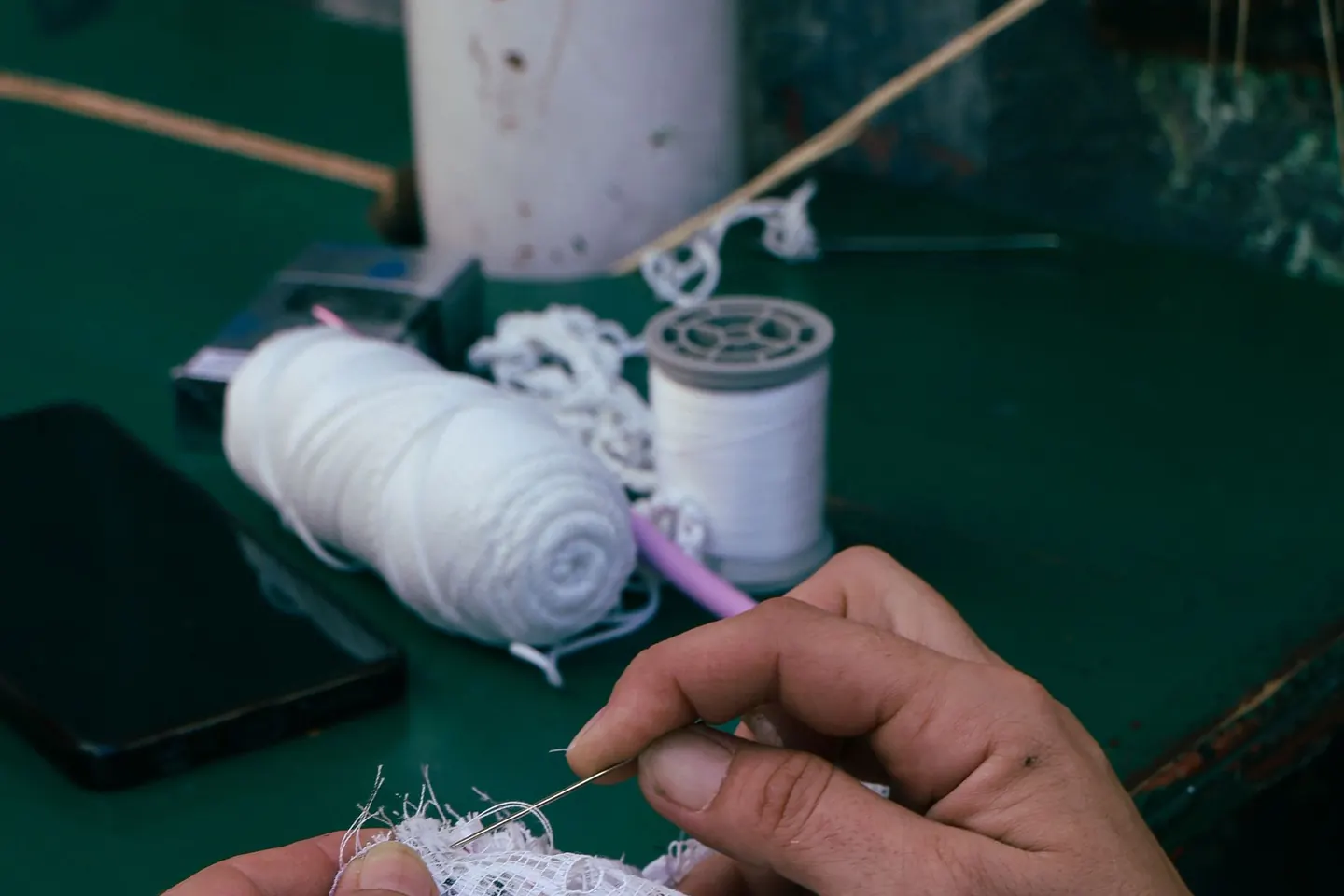 Mains travaillant une broderie sur une dentelle