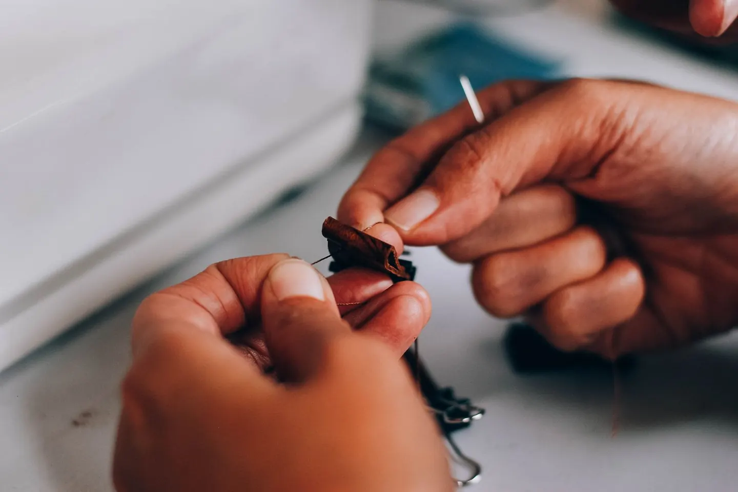 Gros plan sur des mains qui manipulent une aiguille et du fil